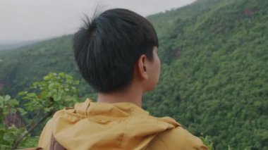 Traveler hiking to the edge of a cliff and look around at the mountain. Sport and travel concept.