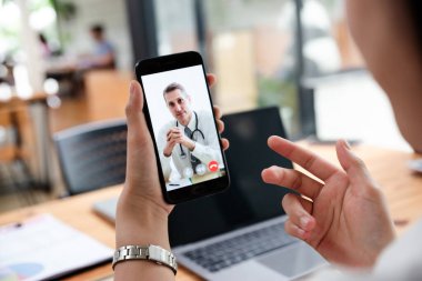 İş kadını ofisten doktorla konuşuyor. Cep telefonunda uzman bir hasta var. Sağlık ve Tıp Konsepti.