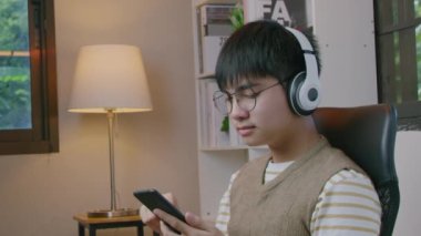 Akıllı telefonu tutan ve oturma odasında müzik dinleyen genç adamın elleri..