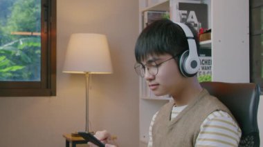 Oturma odasında kulaklıkla müzik dinleyen genç adam..