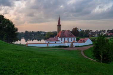 Gatchina, St. Petersburg, Rusya 'da bir sonbahar sisli akşamında, Kara Göl kıyısındaki Manastır Sarayı' nın arka planında günbatımı gökyüzünün görüntüsü