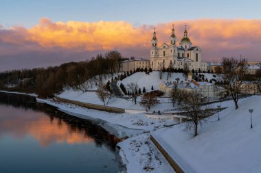 Kutsal Ruhlar Manastırı ve Batı Dvina Nehri kıyısındaki Kutsal Katedral 'de bir kış akşamı pembe bir günbatımı gökyüzüne karşı, Vitebsk, Belarus