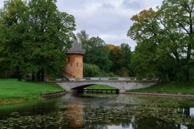 Pavlovsk Sarayı 'ndaki Slavyanka Nehri ve Pill Tower Köprüsü bulutlu bir sonbahar gününde, Pavlovsk, Saint Petersburg, Rusya