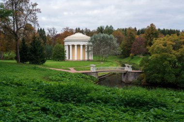 Pavlovsky parkındaki Slavyanka Nehri ve Dostluk Tapınağı üzerindeki demir köprü, sonbahar bulutlu bir sabahta, Saint Petersburg, Rusya