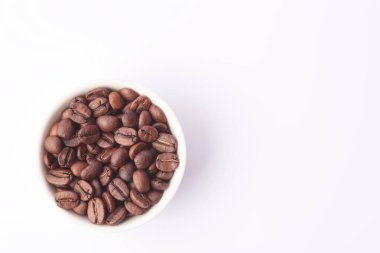 Beyaz arka planda beyaz fincanda kahve çekirdekleri.