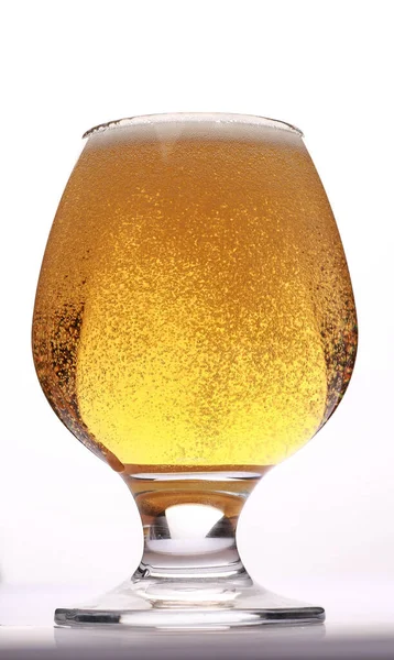 Glass of fresh beer with cap of foam isolated on a white background