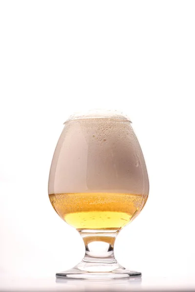 Glass of fresh beer with cap of foam isolated on a white background