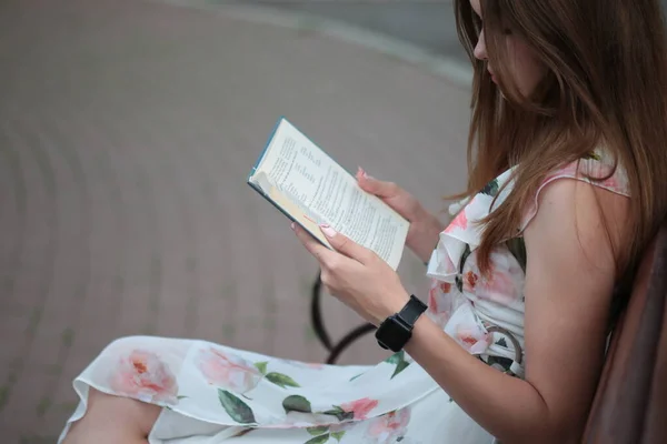 Girl reading a book sitting on a bench outside — Stock Photo, Image