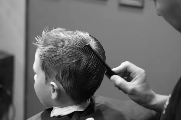 A mão de tatuagem masculina de um barbeiro profissional está segurando uma  tesoura contra uma barbearia de fundo branco e um conceito criativo de  cortes de cabelo