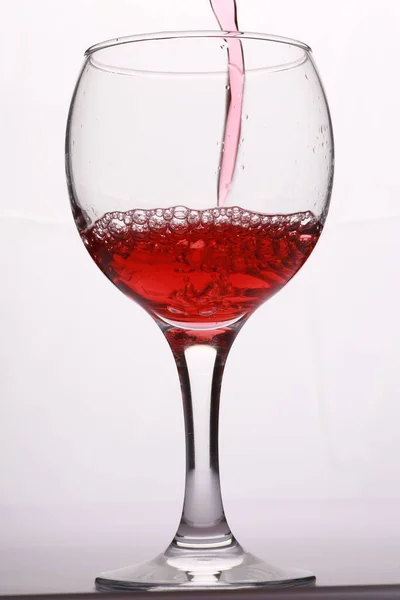 Kırmızı şarap bardağa dökülüyor.