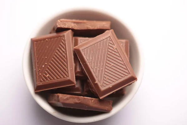 Süt çikolata parçaları beyaz arkaplanda izole edilmiş.