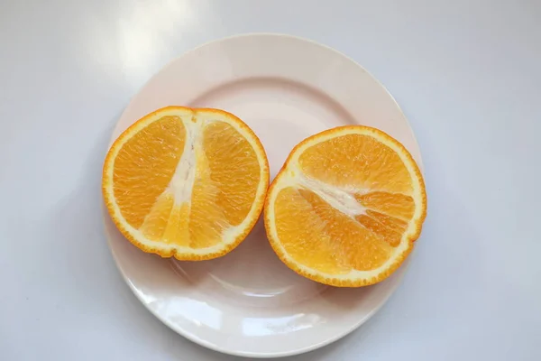 Orange cut in half in a plate on a white background