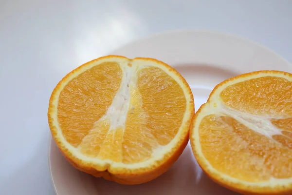 Orange cut in half in a plate on a white background