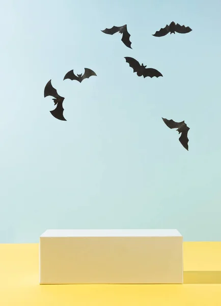 Gökyüzü mavisi arka planda podyum ve yarasaların siluetleriyle modern ürün gösterimi. Ürün Gösterimi ve İş Konsepti için uygundur. Moda Cadılar Bayramı geçmişi.