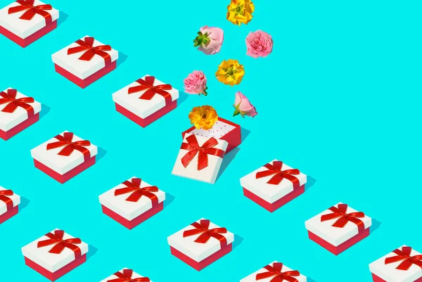 Kırmızı hediye kutularından ve mavi arka planda renkli gül çiçeklerinden oluşan yaratıcı desen. Sevgililer Günü veya 8 Mart kartı.