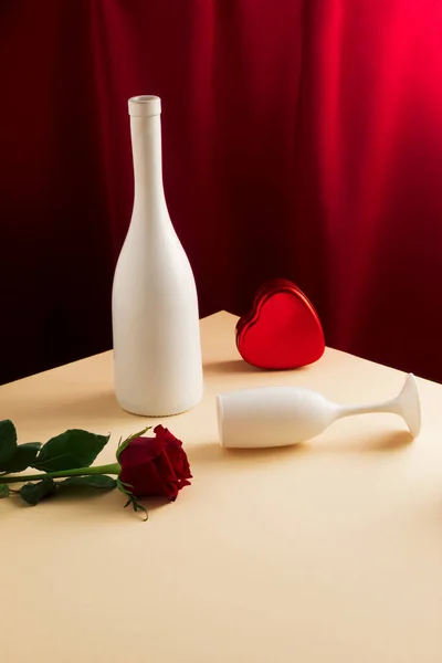 白ワインボトル ガラス 赤バラの花と明るい砂のテーブルの上にギフトボックスとヴィンテージスタイルのコンセプト 絹のような赤いカーテンの背景 レトロバレンタインデーパーティーのコンセプト — ストック写真