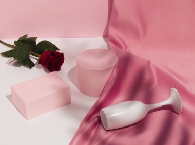 Romantik pastel pembe sevgililer günü kompozisyonu şarap kadehleri, saten perdeler, kırmızı gül çiçekleri ve boş podyumlar. Ürün Gösterimi ve İş Konsepti için uygundur. Modern estetik.