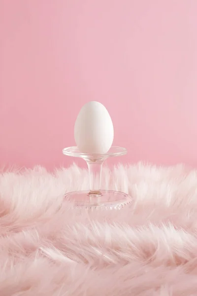 Podyum ve pembe kürk arka planında beyaz yumurtadan yapılmış paskalya kompozisyonu. Asgari tatil kavramı.
