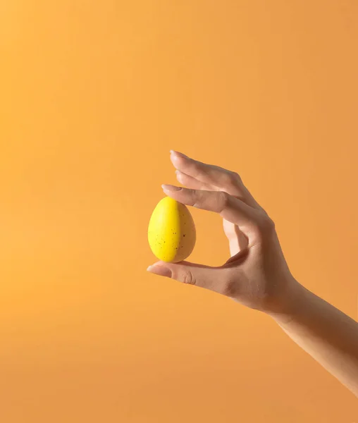 Hermosa Mano Mujer Sosteniendo Huevo Amarillo Contra Fondo Naranja Estilo —  Fotos de Stock