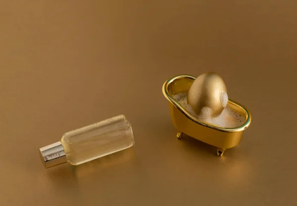 黄金の背景にバスタブ シャボン玉 バスタブボトルで黄金のイースターエッグ 単色組成物 ハッピーイースターの休日 衛生とスパ リラクゼーションのコンセプト — ストック写真