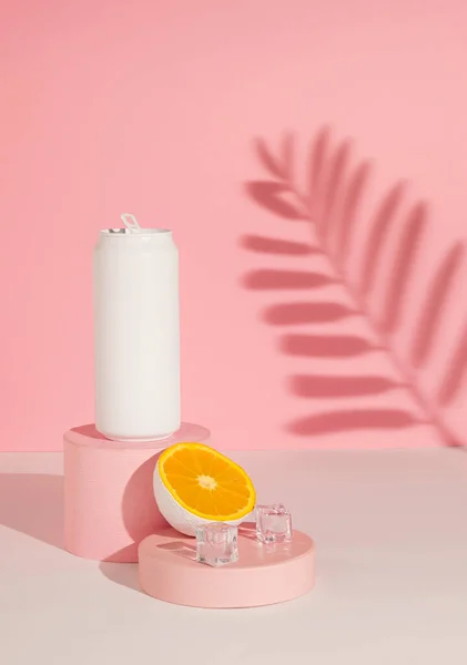Beyaz renkli teneke kutu. Ürün podyumu ve gölgesinde yarı portakallı meyve dilimi. Yaz içkisi konsepti çok az. Pembe estetik..