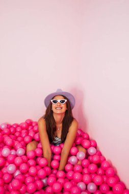 Pembe plastik balonlarla bilardoda eğlenen güzel bir kadın. İzole edilmiş pembe arkaplan. Monokromatik kavram.