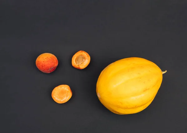 Creative summer layout made of fresh apricot and melon fruit on dark background. Flat lay. Food concept.