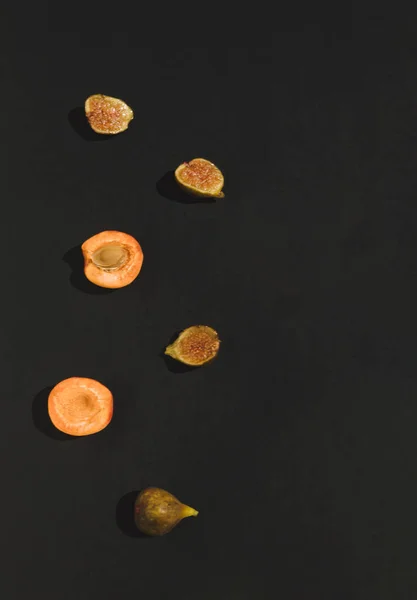 Taze kayısı ve siyah arkaplandaki incirlerden oluşan yaratıcı yaz yerleşimi. Düz yatıyordu. Yiyecek konsepti.