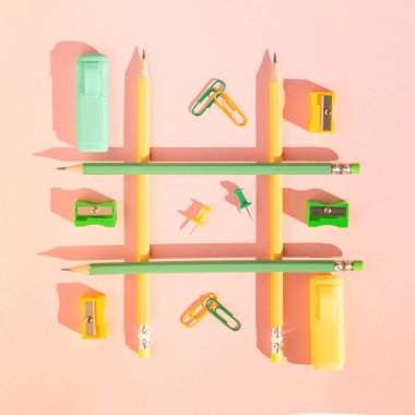 Okul gereçleri, ataç, keçeli kalem ve kalemtıraşlı pastel pembe arka planda tahta kalemler. Yaratıcı düz yatış, üst görünüm. Kırtasiye ile okul konseptine geri dön.