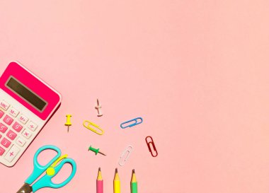 School calculator, pencils, scissors and paper clips on pink background. Back to school concept. Flat lay, top view, copy space.