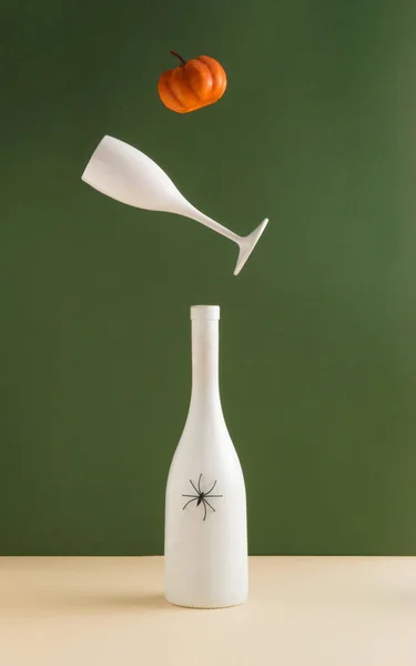 Cadılar Bayramı 'nda balkabağı, şampanya şişesi ve koyu yeşil arka planda cam konsepti. Yaratıcı tatil partisi fikri. Sonbahar renkleri. Mevsimlik arkaplan.