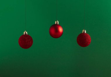 Cesur yeşil arka planda kırmızı takılardan oluşan yaratıcı Noel konsepti. Asgari yeni yıl reklam konsepti. Ürün, promosyon, satış veya sunum için vitrini düzenle.