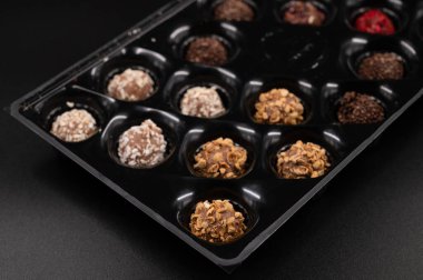 İzole edilmiş siyah arka planda bir kutu şekerin içinde renkli çikolatalı mantarlar..