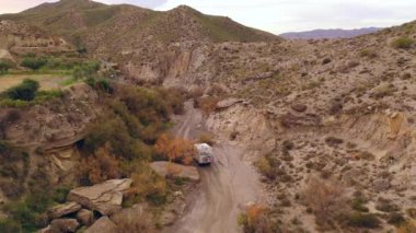 Off road Camper vehicle drives through the Ramblas in the Tabernas desert Drone View