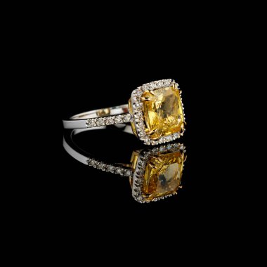 Beautiful white gold ring with yellow sapphire and diamonds on a black background close up clipart