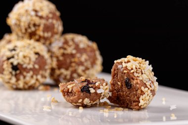 Siyah arka planda beyaz bir tabakta susam tohumlu güzel şekerler.