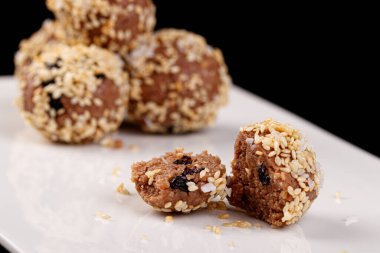 Siyah arka planda beyaz bir tabakta susam tohumlu güzel şekerler.