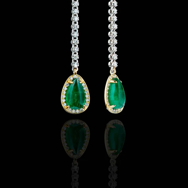 beautiful gold earrings with precious stones diamonds and emeralds on a black background close-up