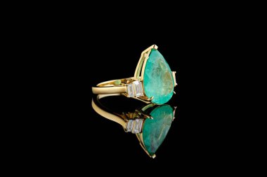 Zümrüt ve siyah arkaplanda elmaslarla güzel altın bir yüzük.