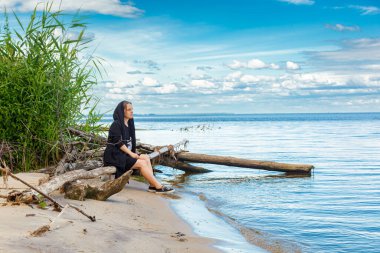 Deniz kıyısında güzel bir kız, mavi gökyüzüne yakından bakıyor.