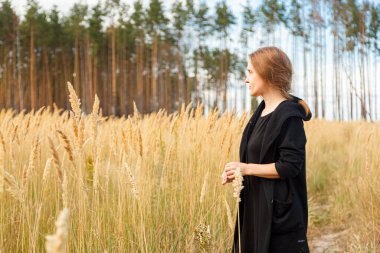 Deniz kıyısındaki bir tarlada güzel bir kız ve bulutlarla çevrili mavi gökyüzü.