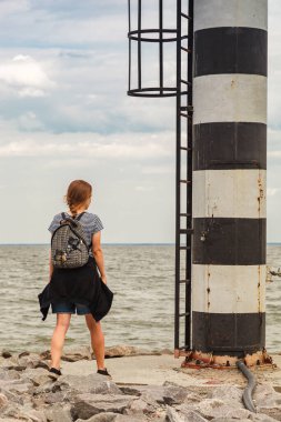 Deniz fenerine bakan güzel bir kız ve bulutlara yakın mavi gökyüzü.