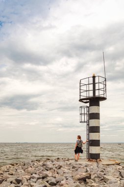 Deniz fenerine bakan güzel bir kız ve bulutlara yakın mavi gökyüzü.