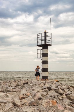 Deniz fenerine bakan güzel bir kız ve bulutlara yakın mavi gökyüzü.