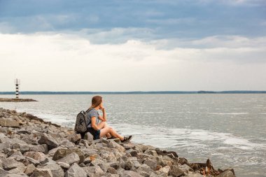 Deniz fenerine bakan güzel bir kız ve bulutlara yakın mavi gökyüzü.