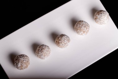 Siyah arka planda beyaz tabakta hindistan cevizli güzel tatlılar.