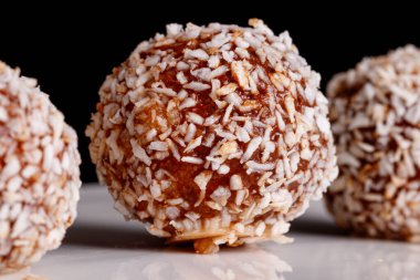 Siyah arka planda beyaz tabakta hindistan cevizli güzel tatlılar.