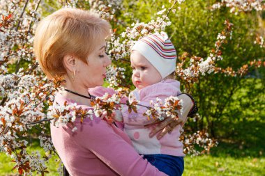 Çiçek açan bir parkta kollarında güzel bir kız.