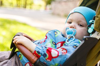 Bebek arabasında emzik taşıyan küçük bir çocuğun portresi.