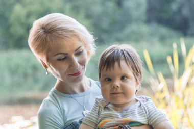 Güzel bir kız gölün arka planında kucağında bir çocuk tutuyor.